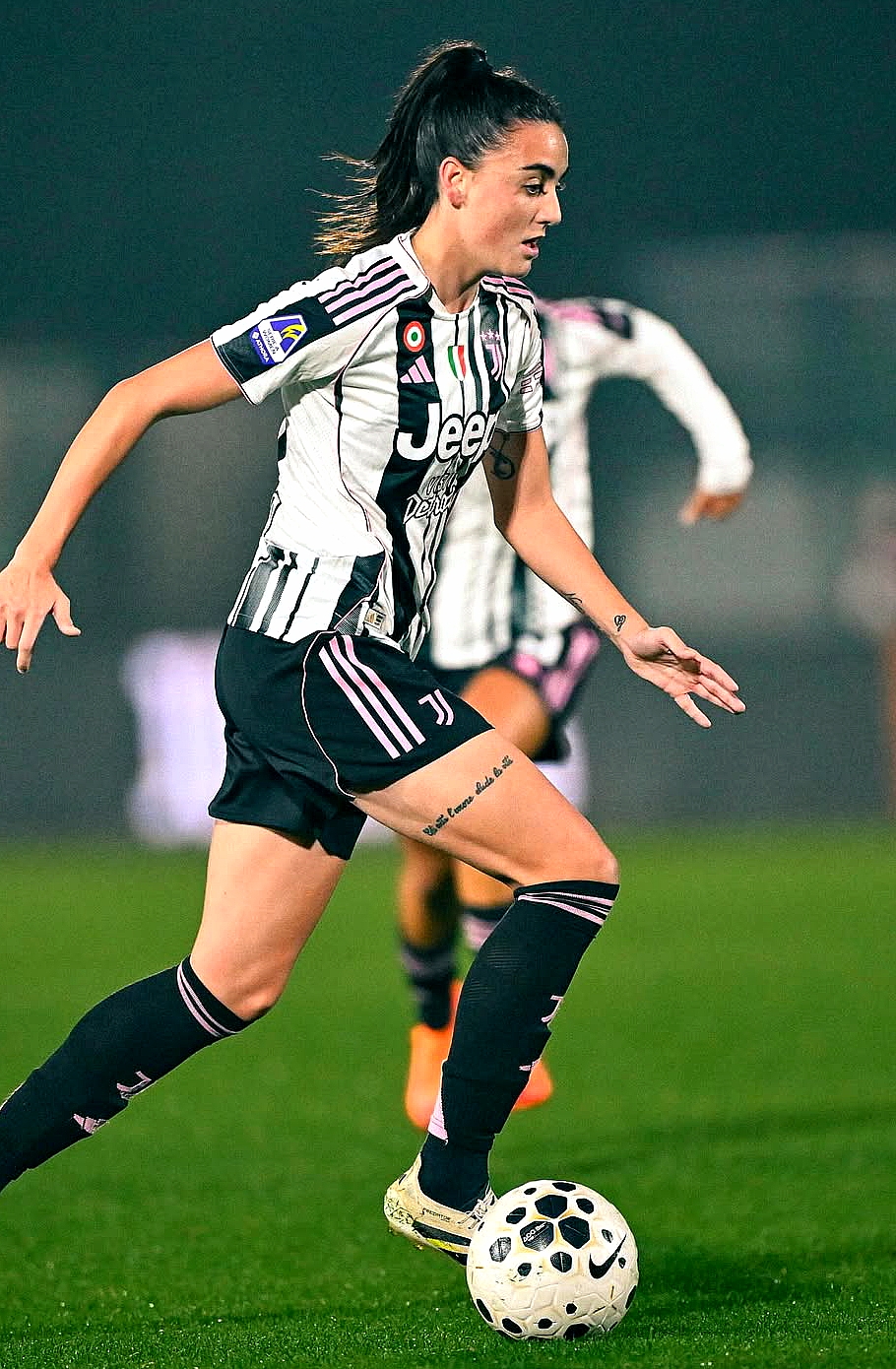 Juventus women player in black and white stripes driving forward