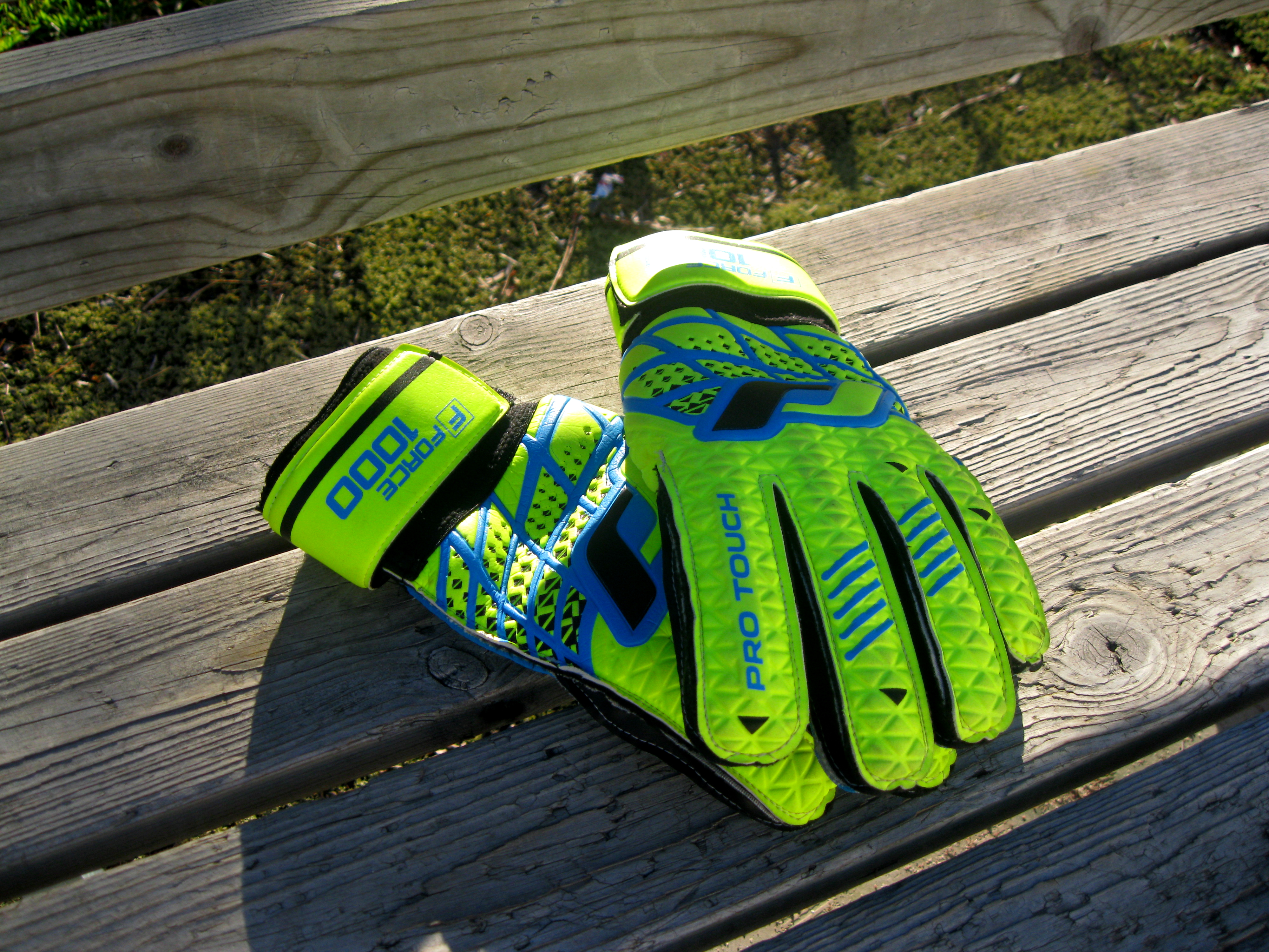 Close-up of goalkeeper gloves beside a football